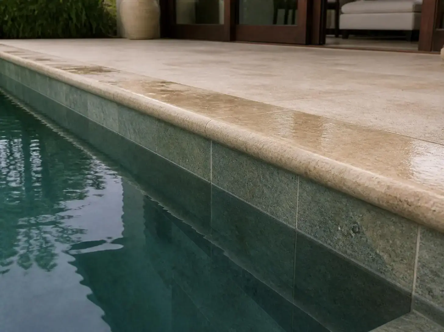 Bullnose natural stone pool coping beside clear pool water