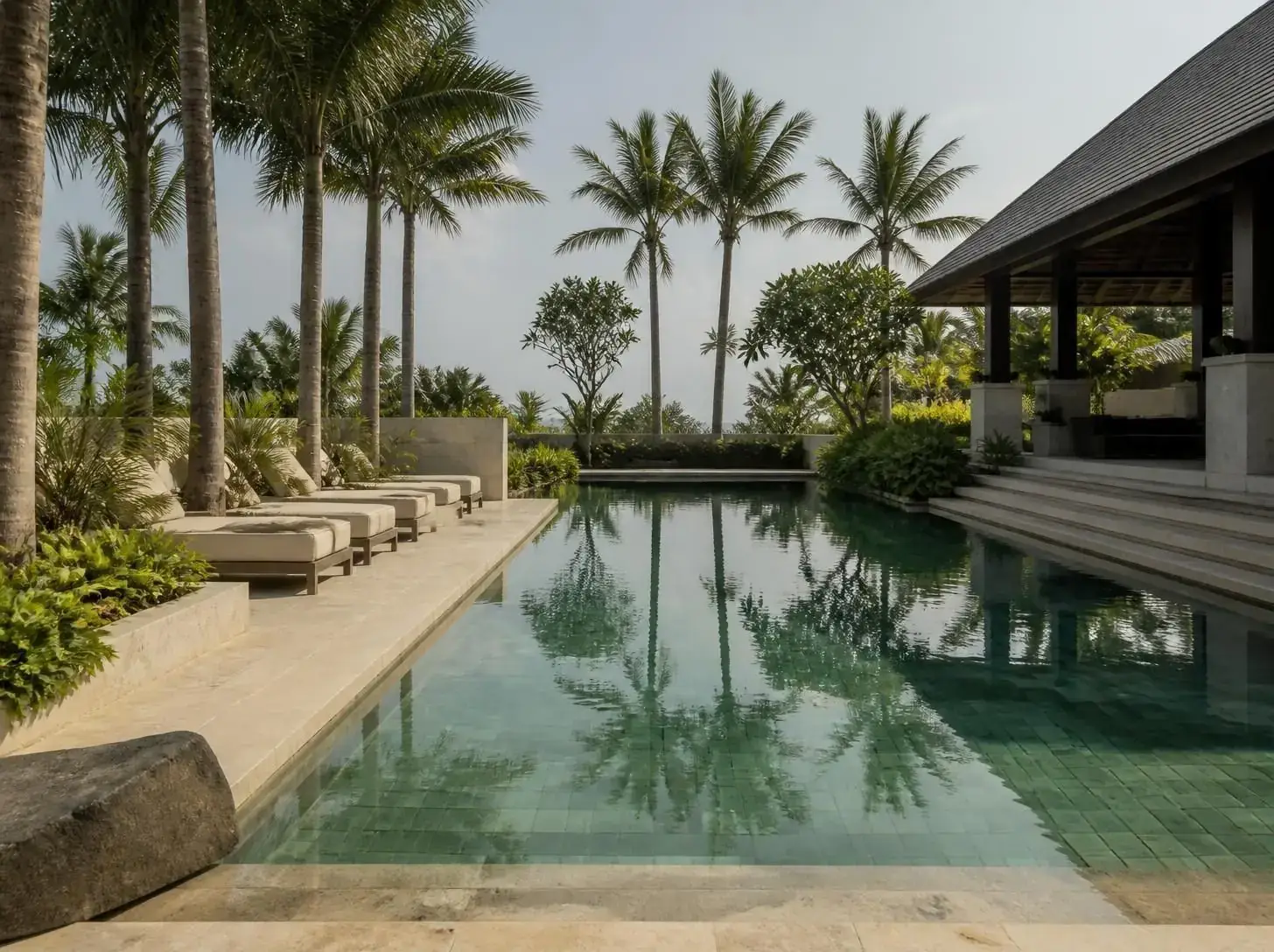 Resort swimming pool clad in Sukabumi Green Stone beside palm trees